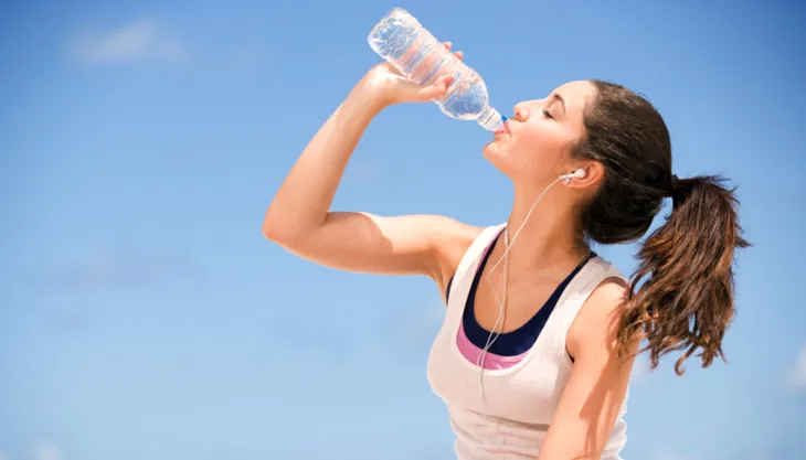 imagen de una joven bebiendo agua e hidratándose