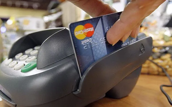 imagen de un datafono pasando una tarjeta de crédito tras una compra