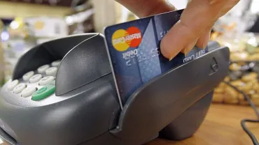 imagen de un datafono pasando una tarjeta de crédito tras una compra